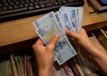 A currency exchange office worker counts Turkish Lira banknotes in front of the electronic panel displaying currency exchange rates at an exchange office in Istanbul, on August 6, 2020 as Turkey's lira set a new record low against the US dollar. - The lira on August 6 was trading at 7.28 against the greenback around 1030 GMT, suffering a loss of more than 3 percent since the start of the day -- the lowest since May when it reached a then-record low of 7.24. The currency also recorded its lowest level against the euro, trading near 8.60 against the European currency at 1030 GMT. (Photo by Yasin AKGUL / AFP)