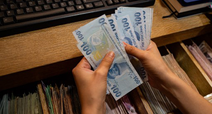 A currency exchange office worker counts Turkish Lira banknotes in front of the electronic panel displaying currency exchange rates at an exchange office in Istanbul, on August 6, 2020 as Turkey's lira set a new record low against the US dollar. - The lira on August 6 was trading at 7.28 against the greenback around 1030 GMT, suffering a loss of more than 3 percent since the start of the day -- the lowest since May when it reached a then-record low of 7.24. The currency also recorded its lowest level against the euro, trading near 8.60 against the European currency at 1030 GMT. (Photo by Yasin AKGUL / AFP)