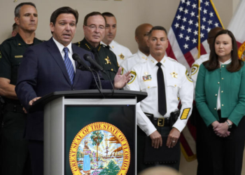 Florida Gov. Ron DeSantis, surrounded by members of law enforcement, gestures as he speaks during a news conference Thursday, Aug. 4, 2022, in Tampa, Fla. DeSantis announced that he was suspending State Attorney Andrew Warren, of the 13th Judicial Circuit, due to "neglect of duty." Looking on at right is Florida Attorney General Ashley Moody. (AP Photo/Chris O'Meara)