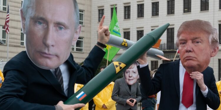 01 February 2019, Berlin: Demonstrators with a Putin and Trump mask and a Merkel mask face each other with rocket models on Pariser Platz. They are protesting with their action against the imminent end of the INF disarmament agreement between Russia and the USA. The agreement on Intermediate Range Nuclear Forces is to be dissolved by the USA. Photo: Paul Zinken/dpa