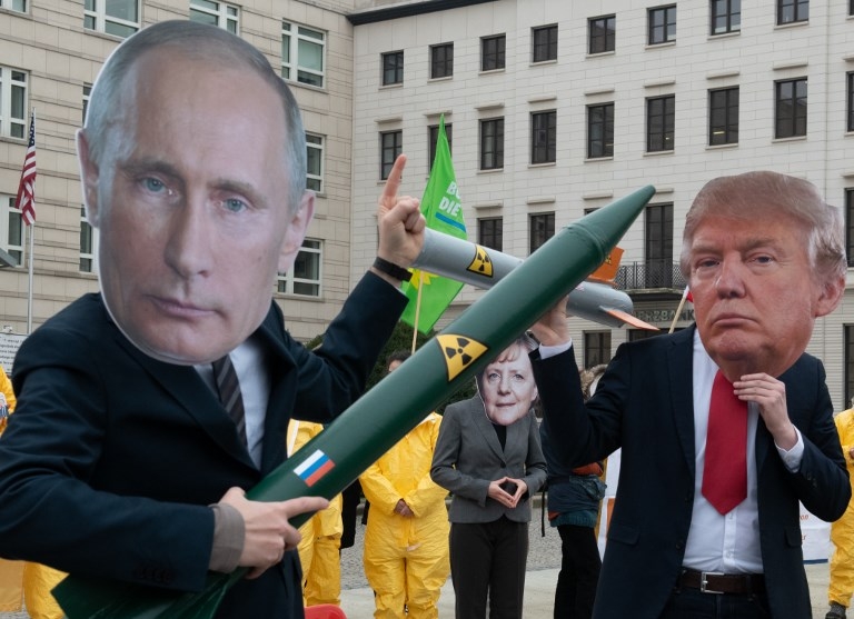 01 February 2019, Berlin: Demonstrators with a Putin and Trump mask and a Merkel mask face each other with rocket models on Pariser Platz. They are protesting with their action against the imminent end of the INF disarmament agreement between Russia and the USA. The agreement on Intermediate Range Nuclear Forces is to be dissolved by the USA. Photo: Paul Zinken/dpa